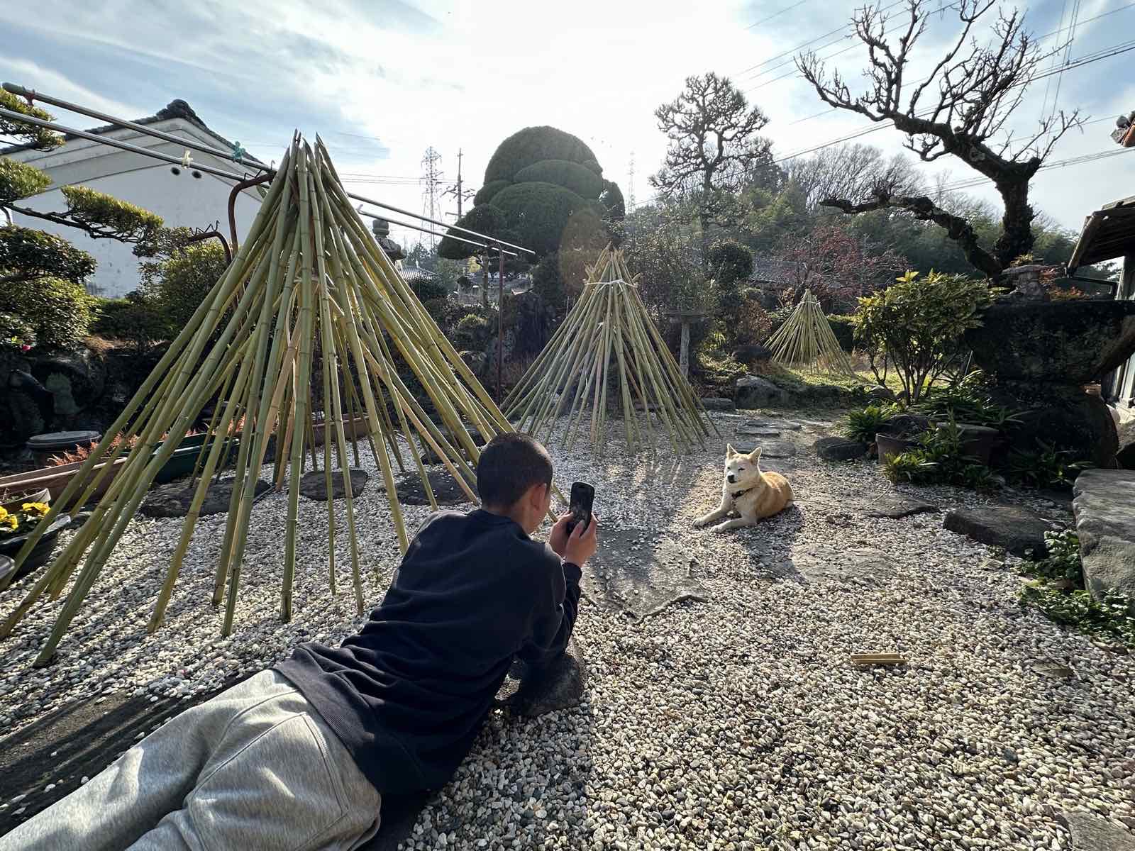 工房の庭で愛犬を撮る子ども
